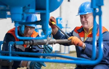 Gasindustrie-Mitarbeiter in Schutzkleidung warten Rohrleitungsanlagen — Symbol für ukrainischen Gasexport und Unterstützung der privaten Förderung