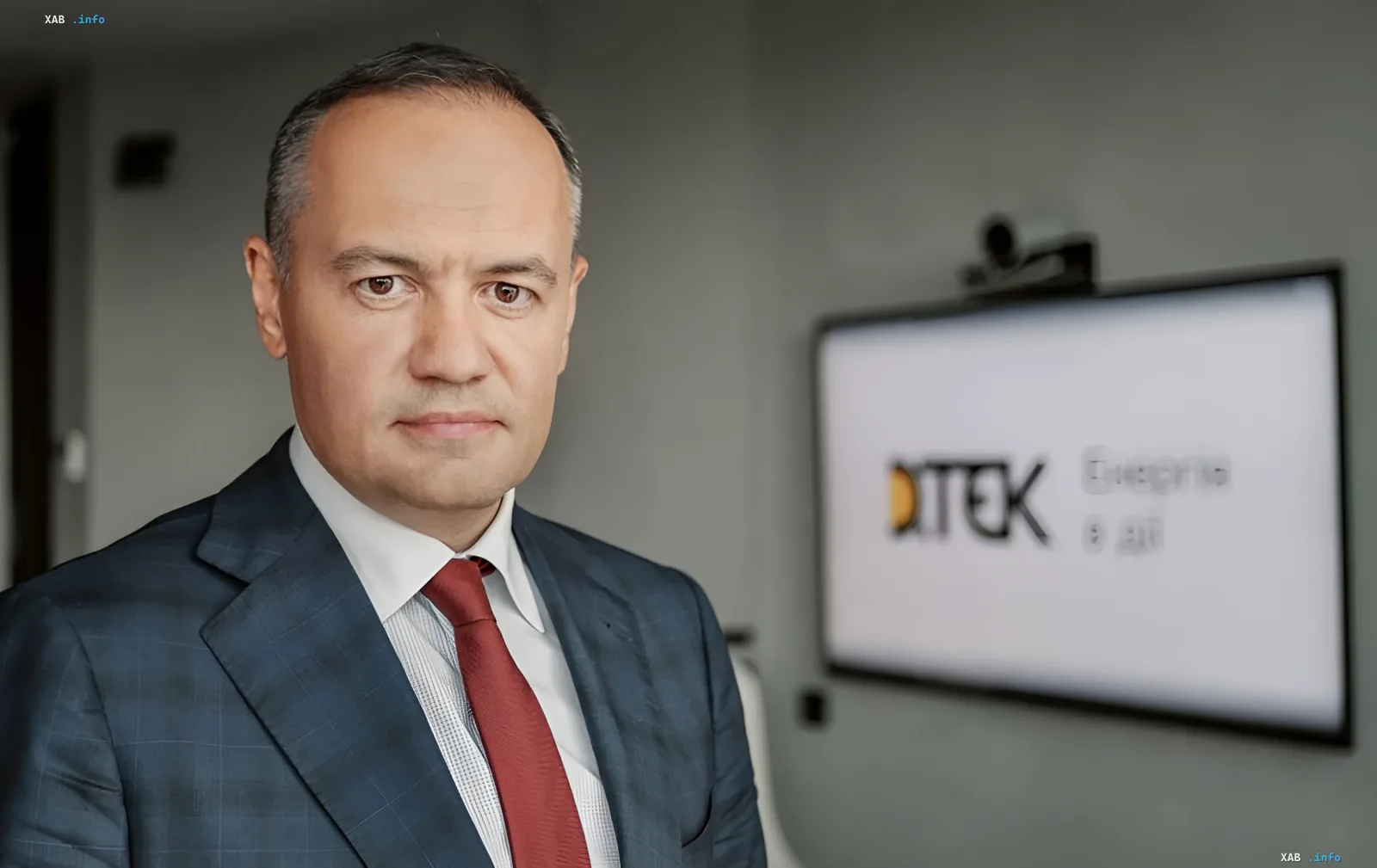 Максим Тимченко в деловом костюме перед экраном с логотипом DTEK — топ-менеджер, вошедший в рейтинг лучших 2026 года на фоне кризиса в энергетике