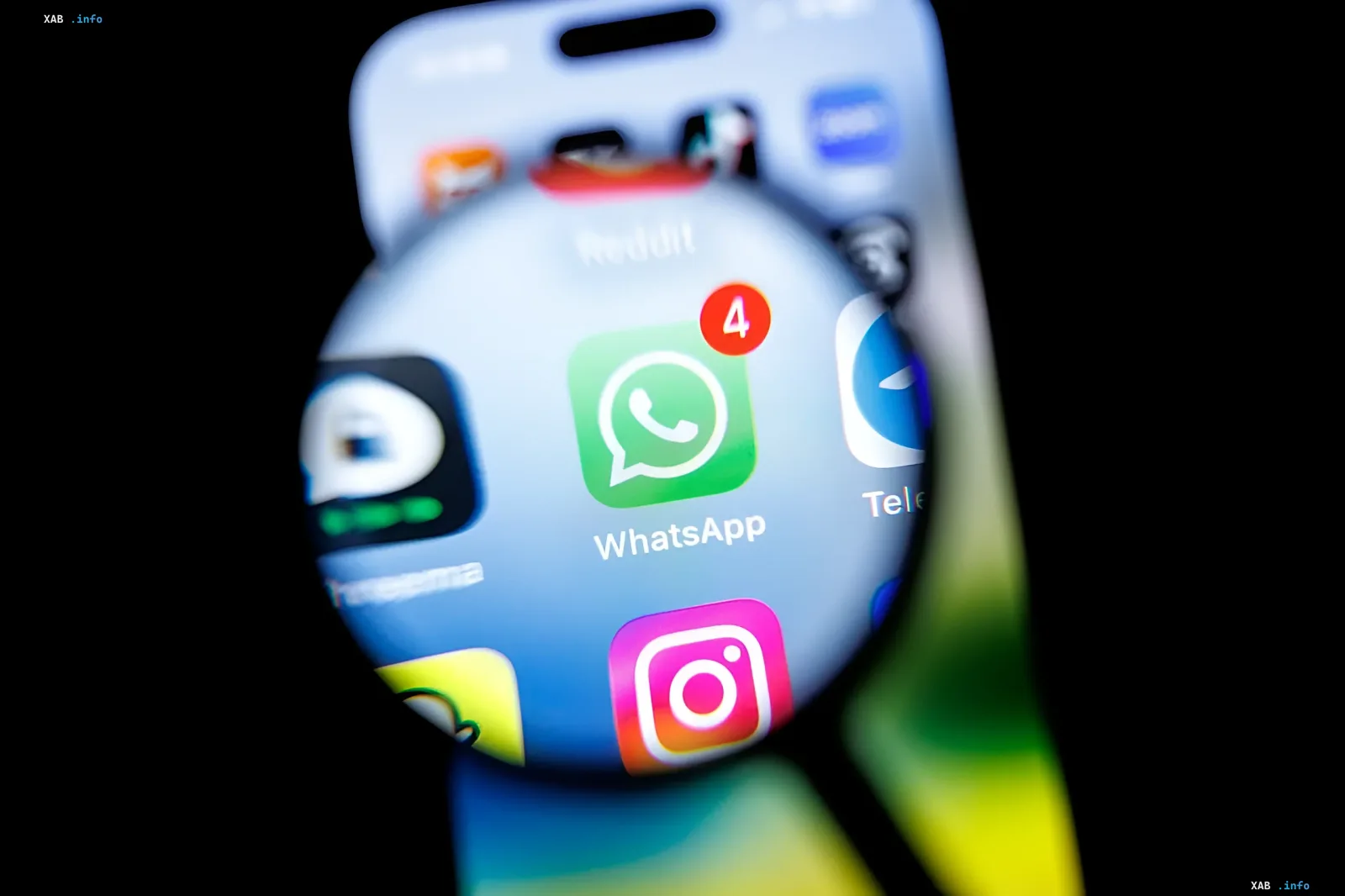Логотип WhatsApp с уведомлением о новых сообщениях, увеличенный лупой на экране смартфона, символизирующий массовую блокировку аккаунтов и технические сбои в работе мессенджера.