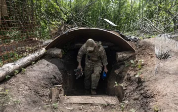 Военный в камуфляже выходит из блиндажа с оборудованием, иллюстрируя тему новых прав для бойцов с судимостью