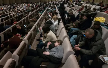 Украинские беженцы в зале временного размещения, мужчины призывного возраста на фоне новостей о новых правилах ЕС