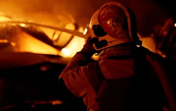 Пожежник у гасить пожежу на заправці, освітлений яскравим вогнем — символ нових атак Росії по українських АЗС