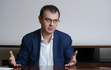 Министр цифрового развития объясняет причины срыва сроков запуска системы еАкциз, жестикулируя за столом в официальной обстановке