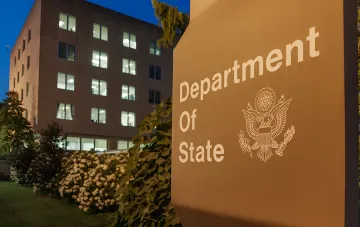 U.S. Department of State sign at dusk in front of an office building, symbolizing new sanctions against Russian military entities