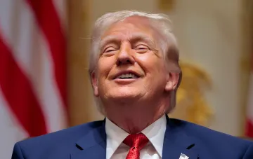 Donald Trump smiling against the American flag — symbol of strict US visa rules with financial deposit up to $20,000 for citizens of 50 countries