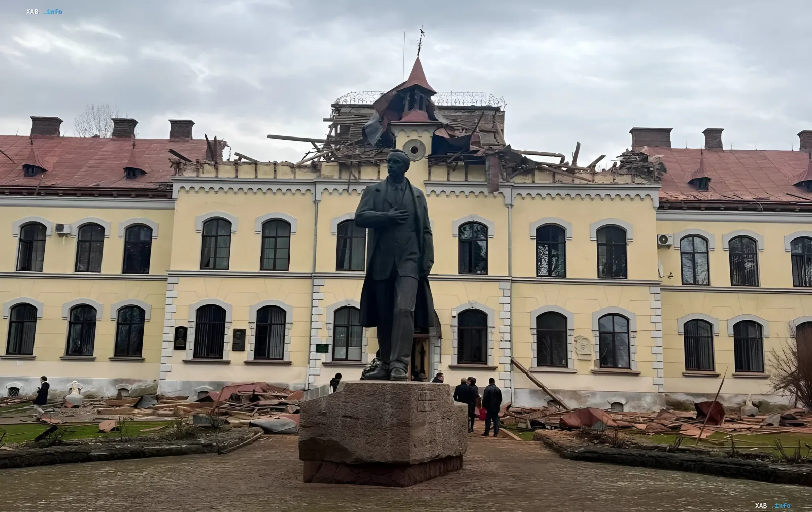 Damaged building with a monument to Stepan Bandera against the backdrop of a destroyed roof