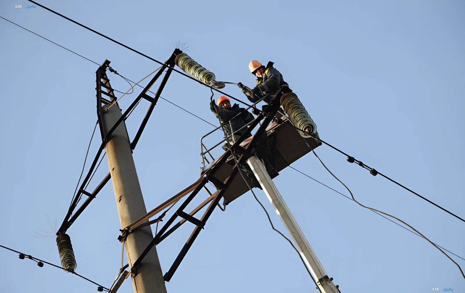 Energieexperten von DTEK Energy reparieren beschädigte Stromleitungen vor einem klaren Himmel
