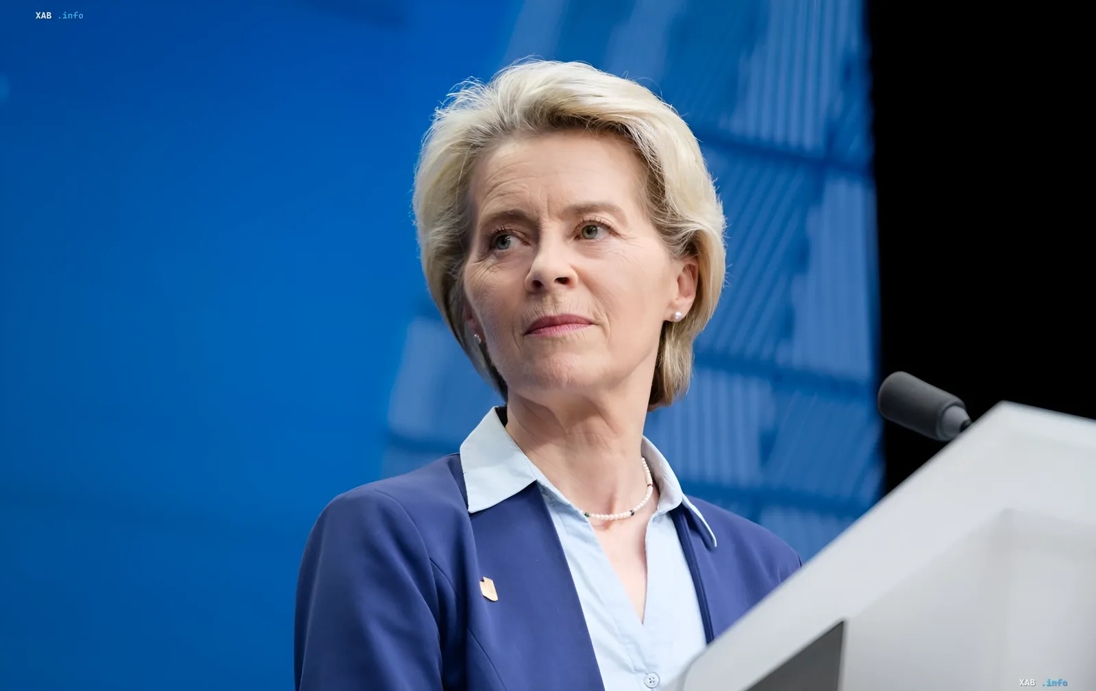 Ursula von der Leyen vor dem blauen EU-Logo, das die Entscheidung symbolisiert, der Ukraine Einnahmen aus eingefrorenen russischen Vermögenswerten zu überweisen
