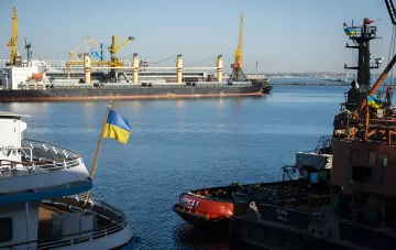 Порт Одесса с украинскими флагами на судах, символизирующий остановку экспорта и кризис в металлургической отрасли из-за угроз обстрелов