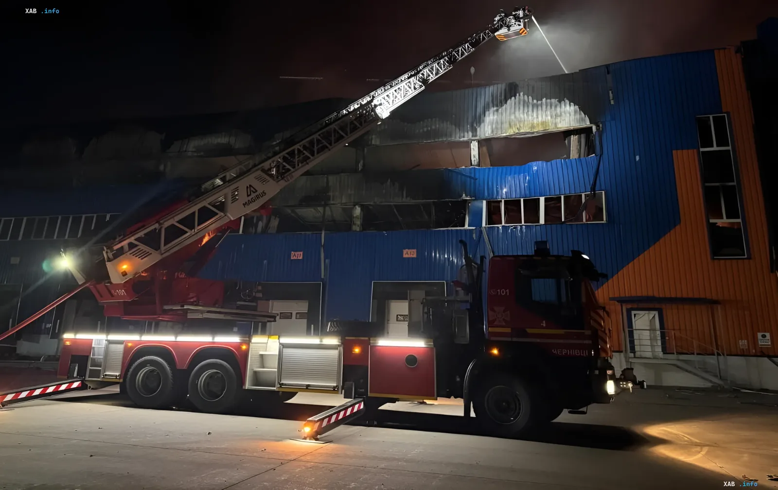 Пожарный автомобиль тушит горящее здание ночью после атаки на Киевскую область