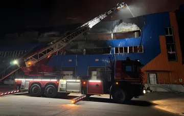 Пожарный автомобиль тушит горящее здание ночью после атаки на Киевскую область