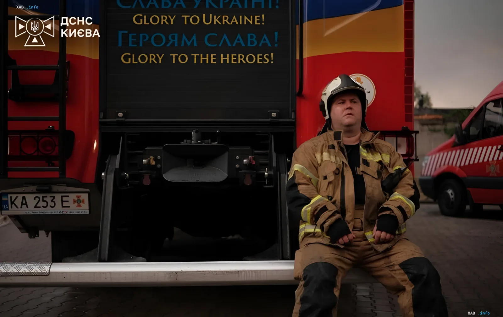 Ukrainischer Feuerwehrmann ruht sich neben einem Feuerwehrauto mit dem Spruch 'Ehre der Ukraine!' nach einem nächtlichen Angriff, bei dem 17 Menschen starben