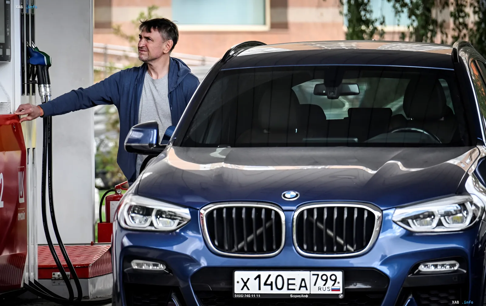 Мужчина заправляет синий BMW на заправке, иллюстрируя тему топливного коллапса в России