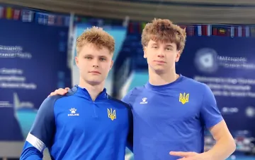 Украинские прыгуны в воду Середа и Гриценко в синих спортивных костюмах с желтым тризубом, стоящие рядом после завоевания бронзы на Евро-2026