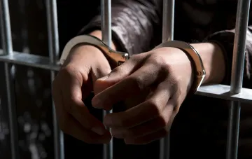 Hands in handcuffs behind bars: symbol of torture committed by a TCC worker in Zakarpattia region