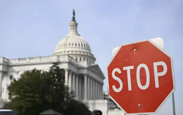 Stop sign in foreground with blurred U.S. Capitol building in background — metaphor for halting legislative changes in Ukraine
