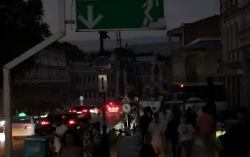 Straßenszene in Georgien während eines massiven Blackouts: dunkle Straßen, Autolichter und Fußgänger im Zwielicht