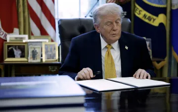Donald Trump at the desk in the Oval Office, signing a document, symbolizing his decision to deny Ukraine Patriot missiles due to conflict with Iran
