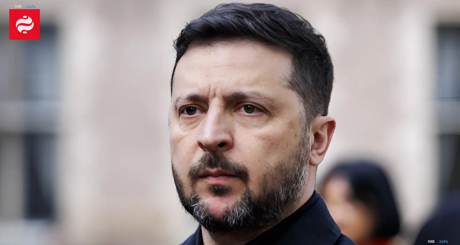 Президент Украины Владимир Зеленский с серьезным выражением лица на фоне размытого здания, иллюстрируя тему сокращения поставок ракет из-за геополитических факторов