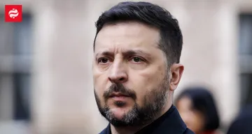 Президент Украины Владимир Зеленский с серьезным выражением лица на фоне размытого здания, иллюстрируя тему сокращения поставок ракет из-за геополитических факторов