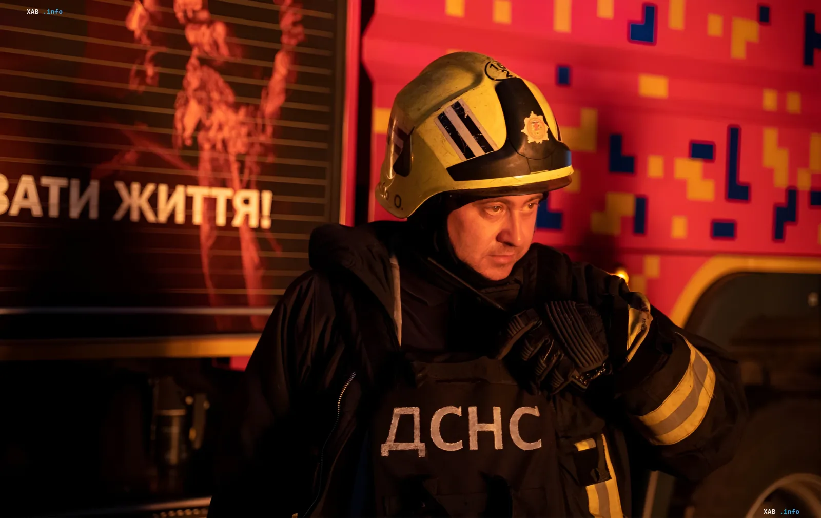 Rettungskraft der DSNS in Schutzausrüstung neben Feuerwehrauto nach KAB-Angriff in Sumy