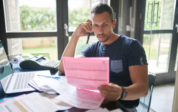 Mann prüft Steuerdokumente und telefoniert, bereitet sich auf eine Steuerprüfung vor
