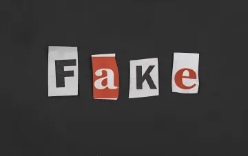 Слово 'FAKE' из вырезанных букв на черном фоне, символизирующее фейковые новости и ИИ-манипуляции с фотографиями погибших украинцев
