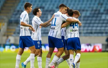 FC Mariupol players in kits with 'abank' logo celebrate a goal on a neutral pitch in the UEFA Conference League