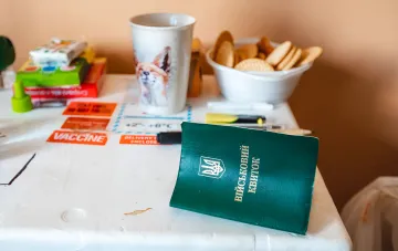 Military ID card on a table with documents and coffee cup — symbol of mobilization and the 'Obereg' registry