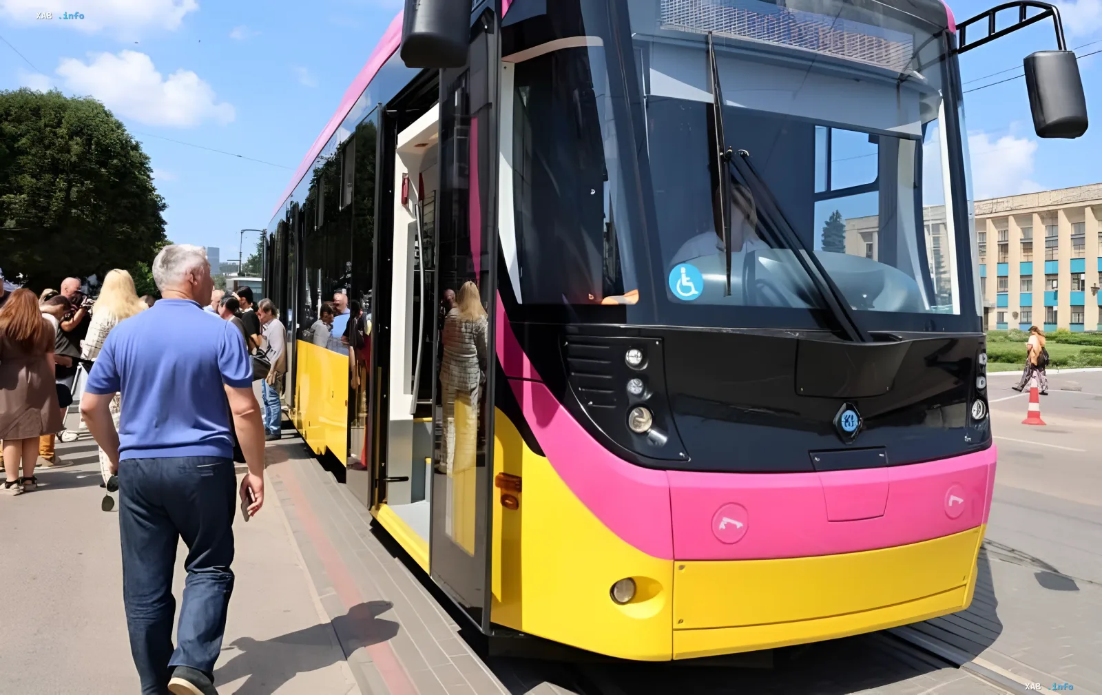 Neuer moderner Straßenwagen mit leuchtendem Design in Kamjanske, Menschen betrachten das Fahrzeug im Rahmen der Flottenerneuerung durch Metinvest-Investitionen
