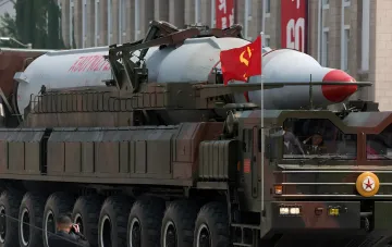 North Korean missile system on parade: ballistic missile on wheeled launcher with North Korean flag