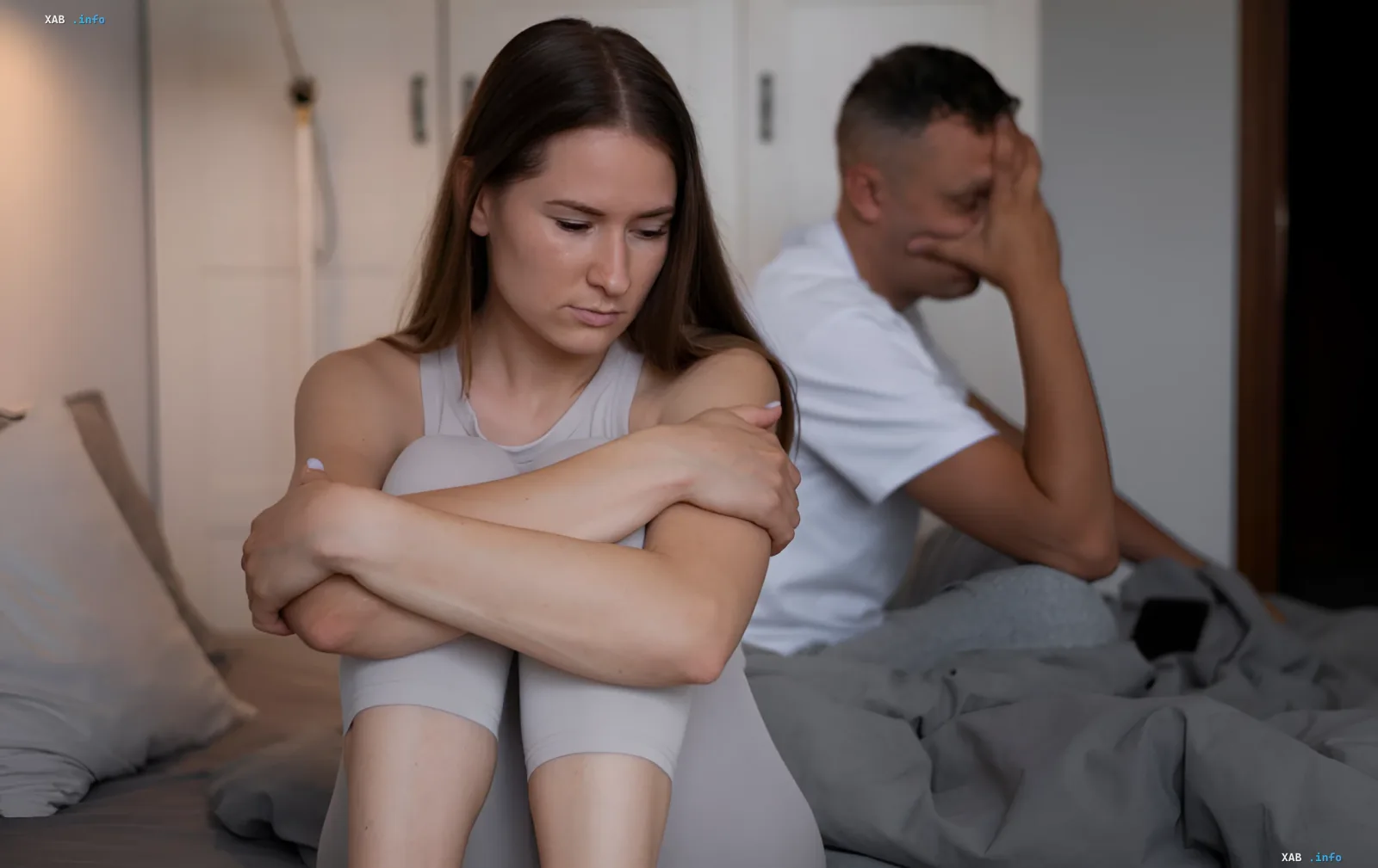 Couple sitting back-to-back in bed, expressing emotional detachment — visualizing the concept of 'quiet divorce'