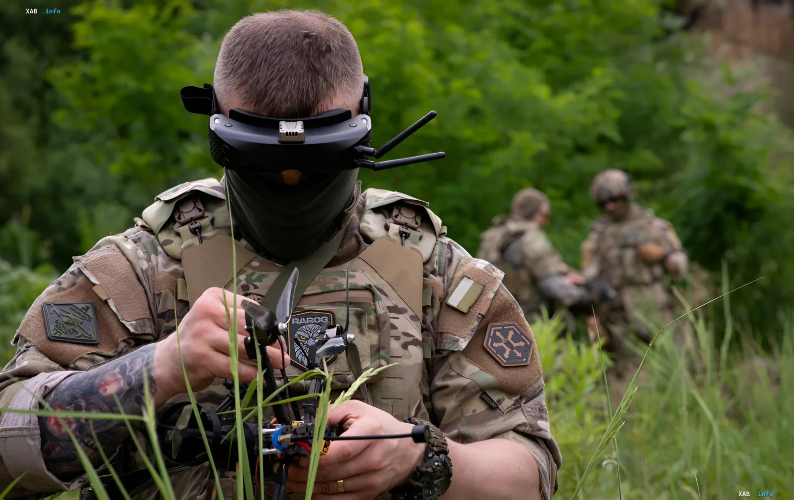 Украинский боец в современной камуфляжной форме и защитной броне с патчем «RAJOG» на груди, использует FPV-дрон в полевых условиях — пример интеграции отечественных технологий в экипировку ВСУ