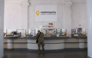 Veteran at the administrator's window in a Ukrposhta branch, illustrating new COD rules requiring RNOКPP