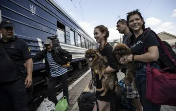 Gruppe von Passagieren mit Hunden und Gepäck am Bahnsteig neben einem Zug der Ukrzaliznytsia, die vereinfachte Ticketbuchung für Gruppen illustriert