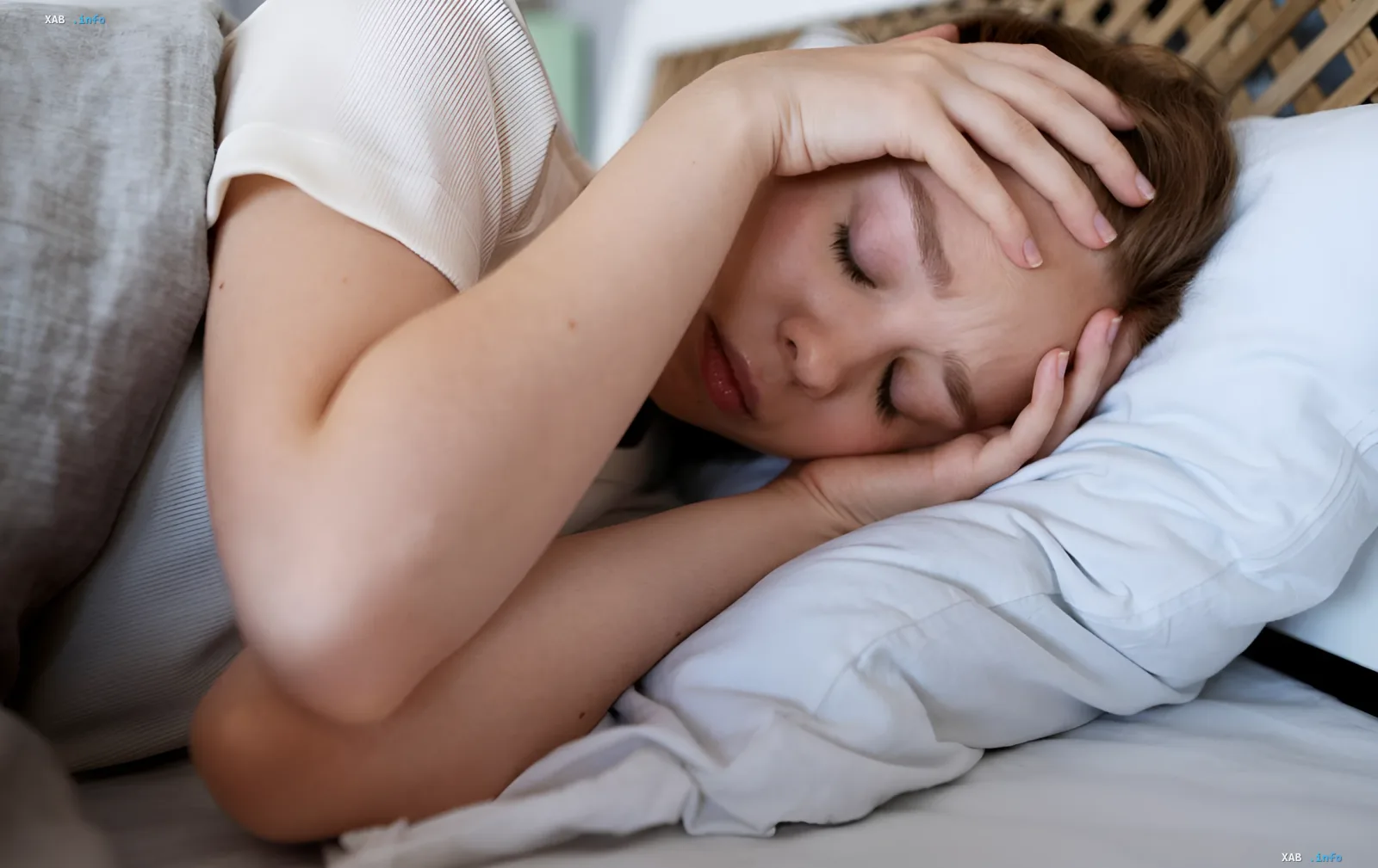 Woman sleeping with hand on forehead, symbolizing an anxious dream or nightmare related to tooth loss
