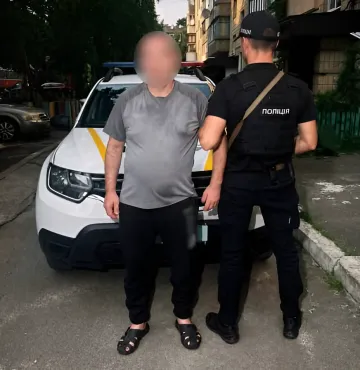Ein Polizist verhaftet einen Mann neben einem Streifenwagen nach einem Vorfall mit einer gefälschten Sprengvorrichtung im Büro eines Versorgungsunternehmens
