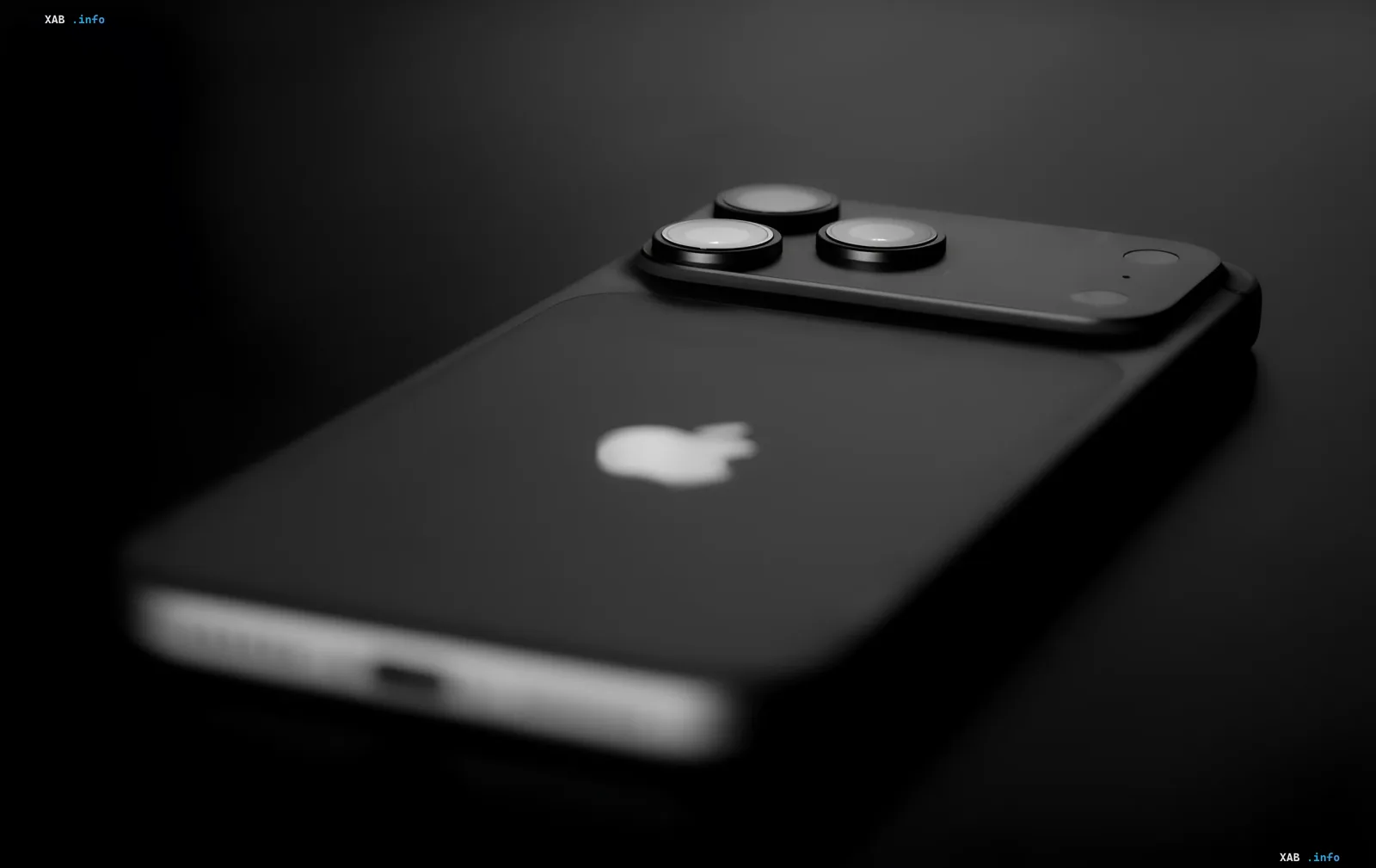 Черный iPhone с тремя камерами и логотипом Apple на темном фоне, иллюстрирующий скрытые функции доступности iOS 26