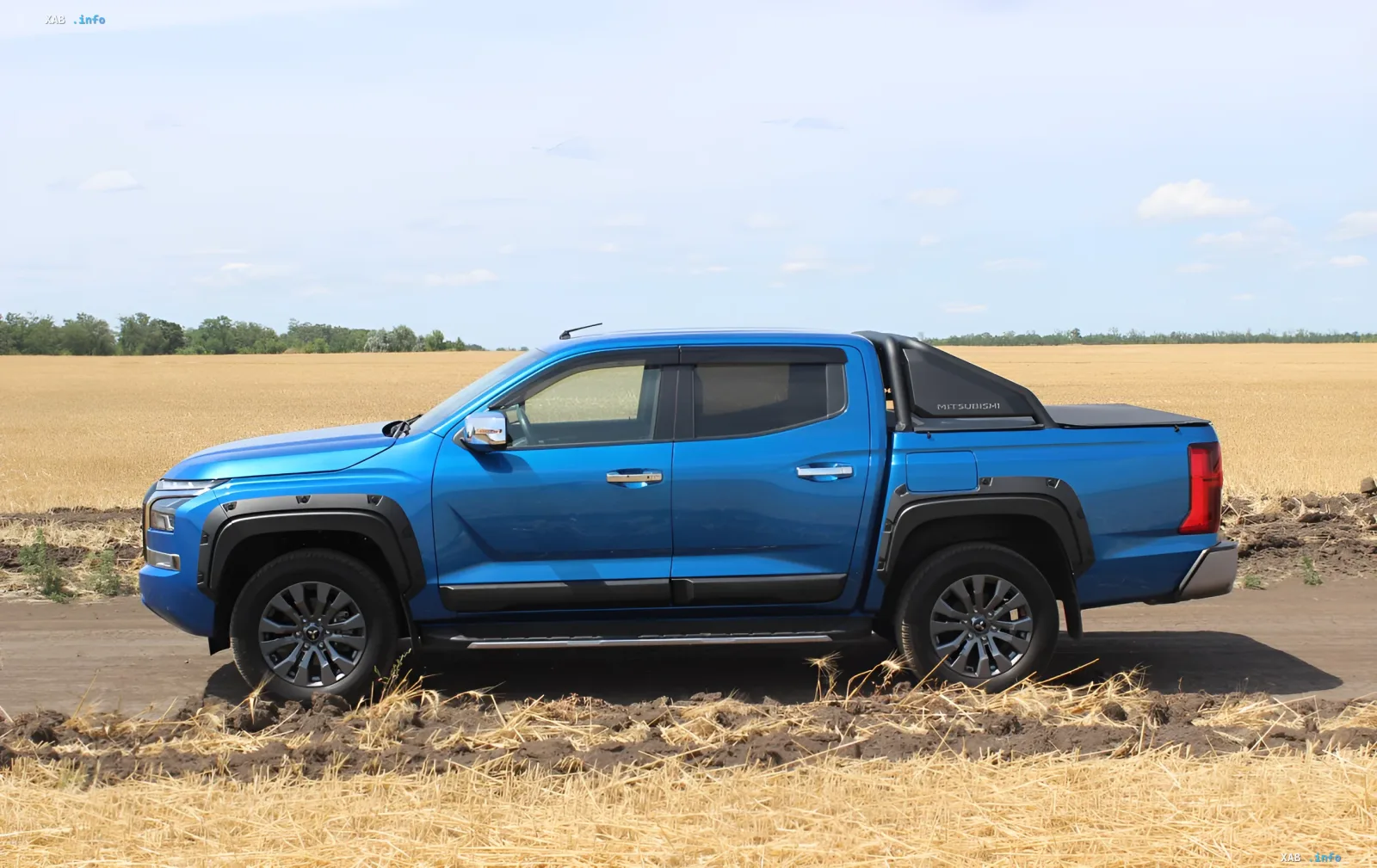 Синий рамный пикап Mitsubishi Triton 2026 года на фоне золотого поля