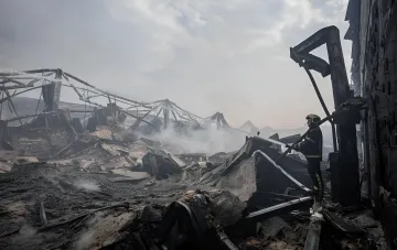 Пожарный тушит остатки сгоревшего склада после обстрела Киева 5 августа, число жертв выросло до двух