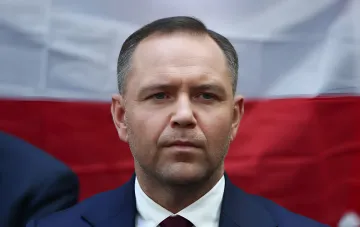Кароль Навроцкий, министр обороны Польши, на фоне польского флага, обсуждает условия военной помощи