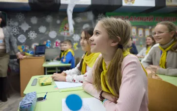 Schoolchildren in yellow scarves in a decorated classroom, illustrating the launch of the 'School Package' program in 2026