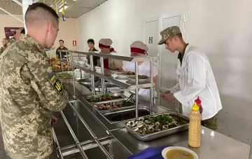 Украинский военнослужащий получает горячее питание в обновленной столовой, демонстрируя реформу системы питания и цифровых закупок.