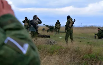 Ukrainische Soldaten im Feld mit einer Artilleriekanone, die Widerstand und Verletzung der Rechte von Kriegsgefangenen durch Russland symbolisieren