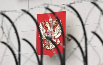 Герб России на фасаде здания, видимый сквозь решетку, символизирующий новые санкции США против РФ