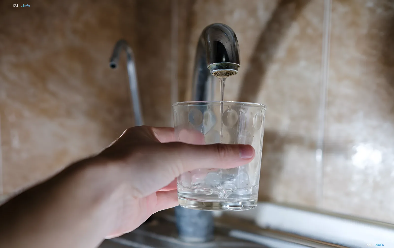 Рука наполняет стакан чистой водой из крана — символ повседневного потребления, которое в Харькове станет дороже в три раза из-за кризиса водоснабжения