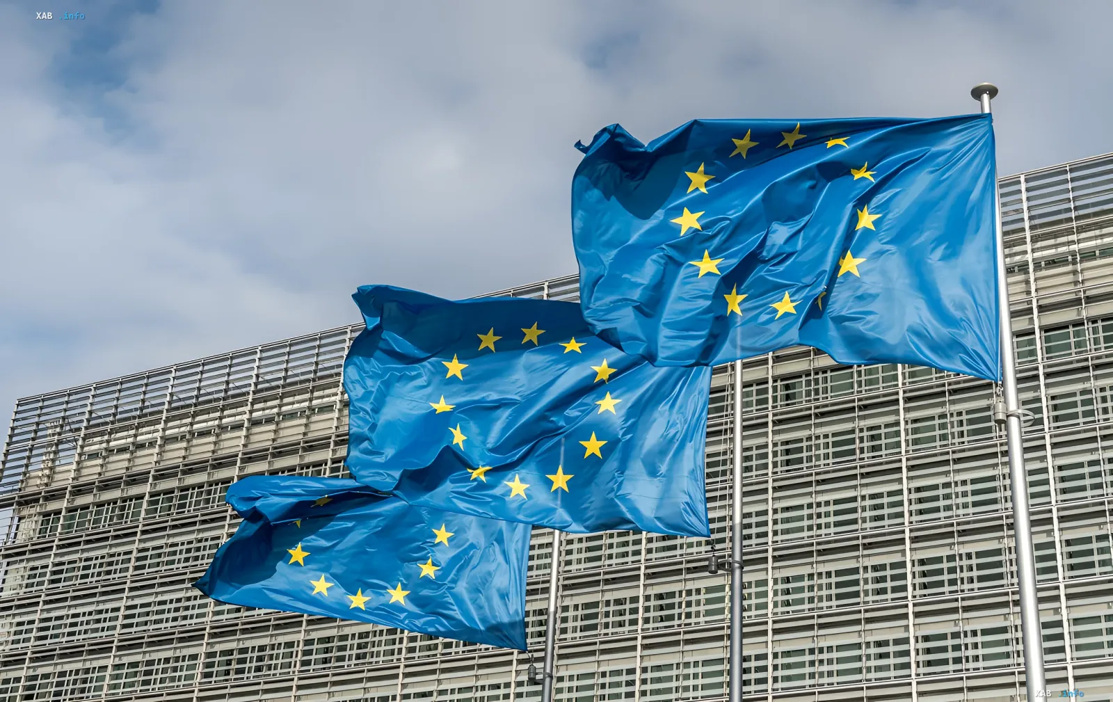 European Union flags waving in front of the European Parliament building, symbolizing political decisions on the confiscation of Russian assets in the context of French elections and Trump's plans