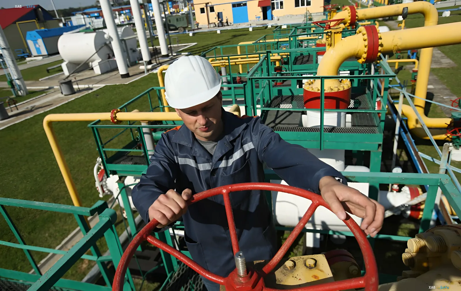 Рабочий в каске управляет красным вентилем на газопроводе, иллюстрируя тему энергетического кризиса в Европе и Германии в зимний сезон 2026 года