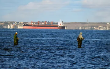 Fischer in den Dardanellen vor dem Hintergrund eines Frachtschiffs: Symbol der Verwundbarkeit der Seewege nach den Einschränkungen der Türkei aufgrund von Drohnenangriffen