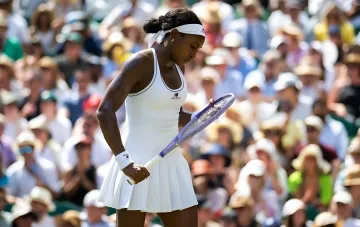 Теннисистка в белой форме с ракеткой на фоне трибун — символ дебатов WTA о генном тестировании для Олимпиады-2028